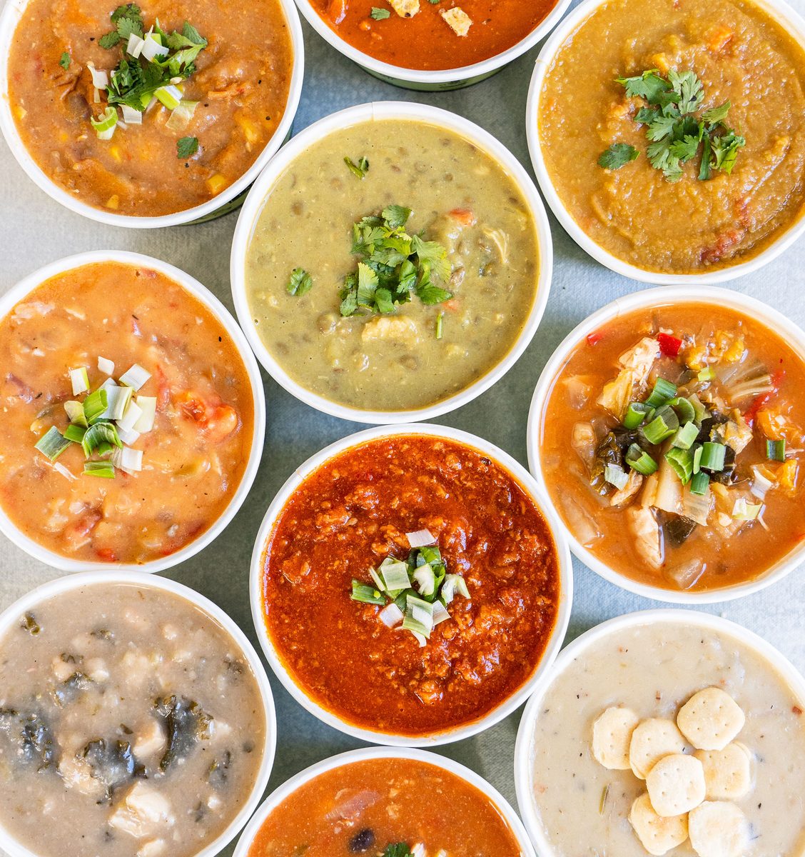 A spread of signature soups served in white cups, viewed from above