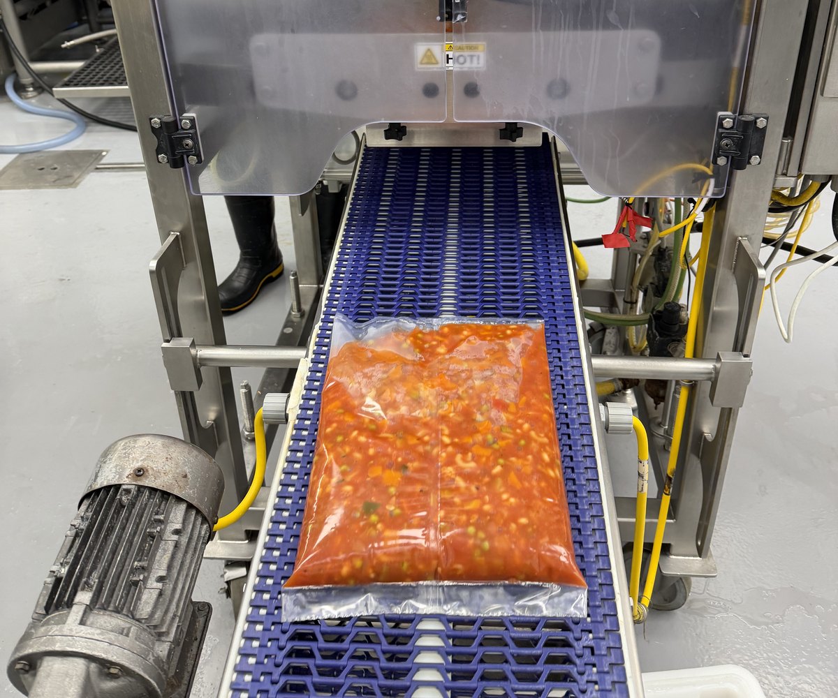 A filled bulk soup pouch leaving the sealer on the packaging conveyor